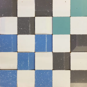 A wood paneling solution made from used wood, with white, blue, turquoise and black pieces, organized like a chess board.